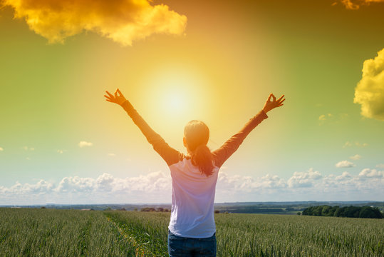 Back view of a woman with her arms raised to the sun