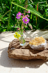 Flowers and crystals! Healing citrine crystal cluster, mini glass vase of fresh cut flowers. Nature and healing crystals shot at wood table outside. Cute witchy bohemian outdoorsy whimsical display