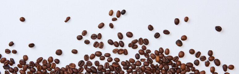 panoramic shot of scattered brown roasted beans on white background