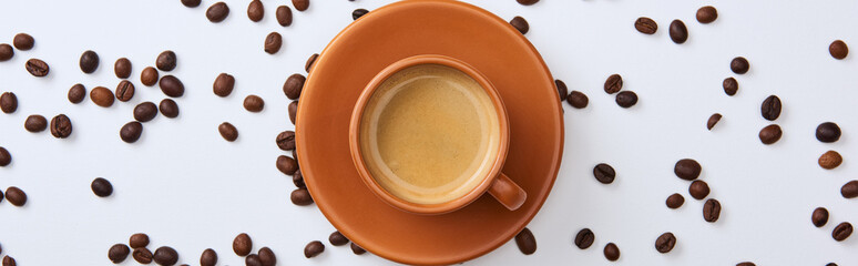 top view of delicious coffee in cup near scattered beans on white background, panoramic shot © LIGHTFIELD STUDIOS
