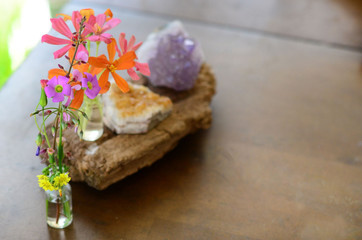 Amethyst and Citrine clusters on a wooden table, small vase of fresh flowers. Shot on macro lens in natural lighting. Bright colors, healing crystal clusters. Hippie natural healing and fresh herbs. 