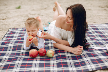 Family sitting on a sand. Mother in a white dress. Cute little boy