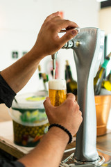 Barman hands at beer tap pouring a draught lager beer serving in a restaurant or pub