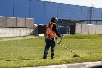 the lawn-mower cuts the grass in the afternoon, using a protective mask
