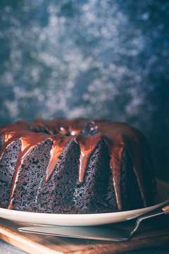 Devil's food cake covered with melted chocolate and a bowl of fresh raspberries