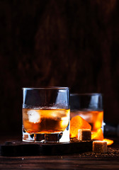 Old Fashioned - classic alcoholic cocktail with bourbon whiskey, bitter, cane sugar and ice in retro glasses on vintage bar counter, place for text