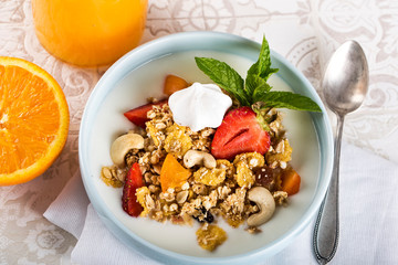 Breakfast. Muesli with milk or yogurt, nuts and strawberries, orange juice and orange