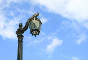 Fototapeta na wymiar Vintage Black Lamppost Against Cloudy Blue Sky