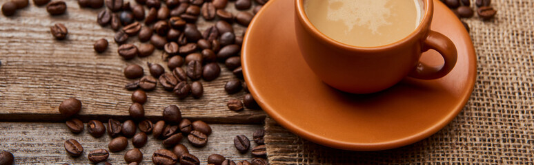 panoramic shot of coffee beans near cup of coffee on wooden background