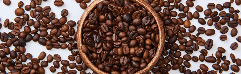 panoramic shot of coffee roasted beans in wooden bowl on white background