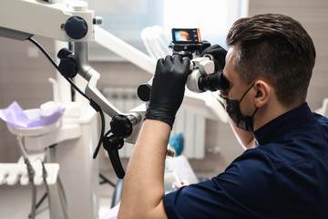 Doctor making teeth examination research survey using microscope in dentistry. Dentist is treating...