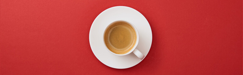 top view of white cup with coffee on saucer on red background, panoramic shot