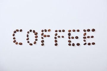 top view of coffee lettering made of coffee beans on white background