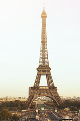 Fototapeta premium Paris/France - 10 23 2018: The Eiffel Tower in the day bright sun lights. The road under the huge tower, red lights of cars. Famous architectural monument and construction, symbol of France and Paris.