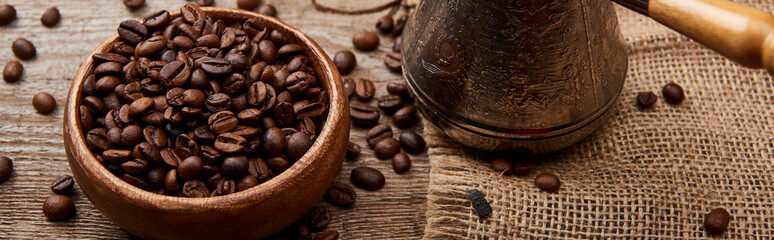 Fototapeta premium panoramic shot of cezve near coffee beans in bowl on wooden background