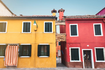 Two old painted yellow and red painted facade with pipes and a tiled brown roof. Closed and open wooden shuttered windows. A narrow passage between the houses, a narrow street. Vacation and tourism.