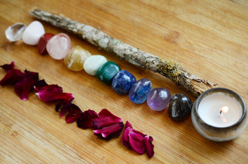 Rainbow Healing Crystals on wood table. Witches candle and fresh rose petals, rainbow stones. Clear Quartz, Pink Calcite, Jasper, Calcite, Malachite, Green Quartz, Fluorite, Sodalite, Amethyst, Onyx