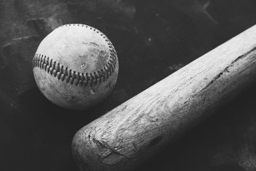 Grunge baseball with wooden bat in black and white for vintage style sports concept close up.