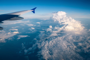 Fototapeta premium wing of the plane against the blue sky with clouds. view from eluminator to the wing of the aircraft against the sky. Concept: flight, vacation, tourism.
