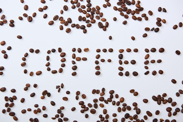 top view of coffee lettering made of brown coffee beans on white background