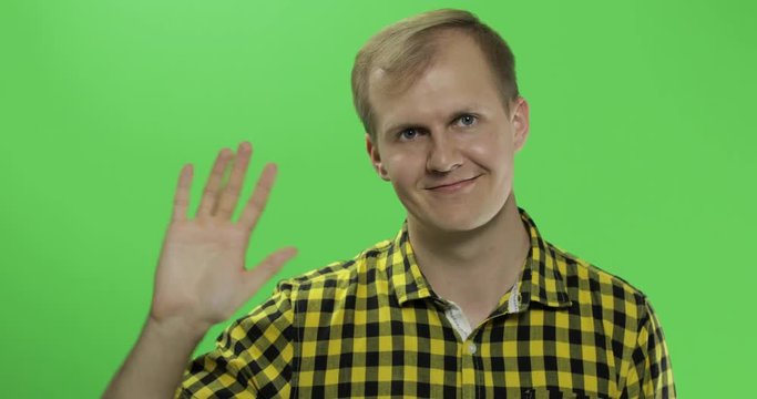 Handsome caucasian man waves and saluting on green screen chroma key