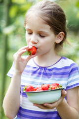 Girl eats red strawberries.