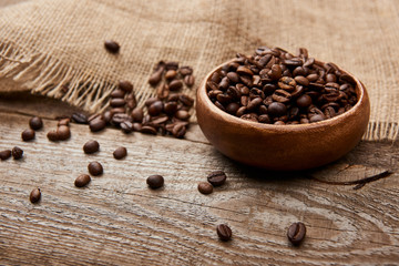 fresh roasted coffee beans in bowl near sackcloth on wooden board