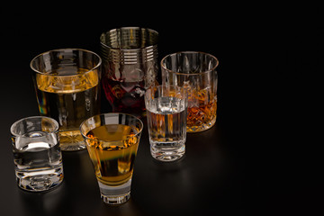 Strong alcoholic beverages, glasses and glasses, in the presence of whiskey, vodka, rum, tequila, brandy, cognac. on dark old background with selective focus
