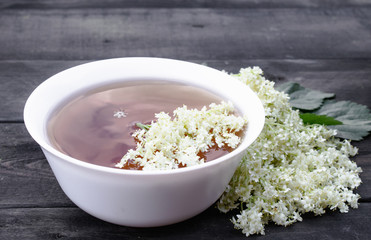 Elderberry tea with flowers on a wooden table.