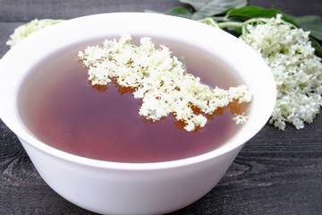 Elderberry tea with flowers on a wooden table.