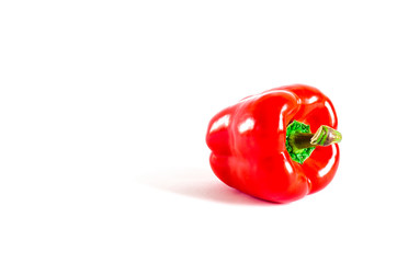 Juicy red pepper with a green tail lies on a white background