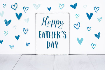 Happy fathers day text on sign board for the best dad in the world with cute little blue hearts on white background