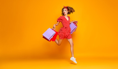 concept of shopping purchases and sales of happy young girl with packages  on yellow background
