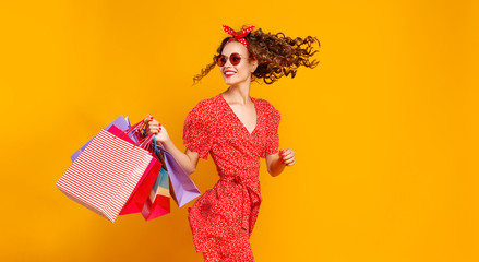 concept of shopping purchases and sales of happy young girl with packages  on yellow background