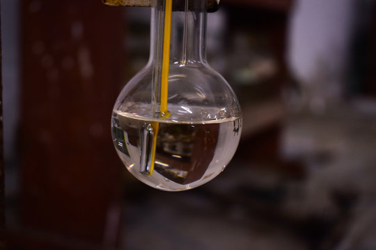thermometer in a round bottom flask with transparent solution in chemistry laboratory