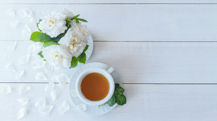 Fototapeta na wymiar morning tea: a Cup of tea and a bouquet of white roses. flowers and tea on the table top view.