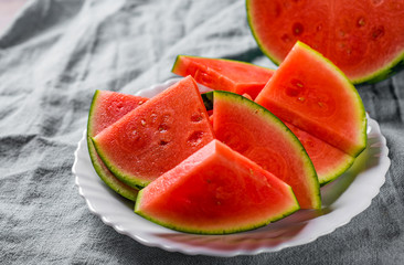 Cut slices of juicy watermelon on white plate on wooden table background