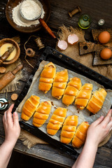Overhead shot of delicious homemade baked sausages rolled in dough on baking tray on wooden rustic table