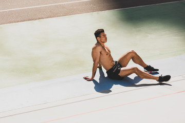 tired handsome mixed race sportsman sitting at stadium