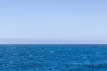 Obraz premium Seascape with sea horizon and almost clear deep blue sky