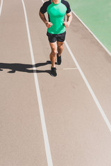 cropped view of sportsman in sportswear running at stadium