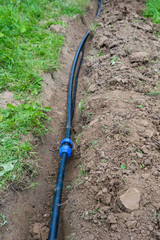 black pipe lying on a dug-out trench, close-up