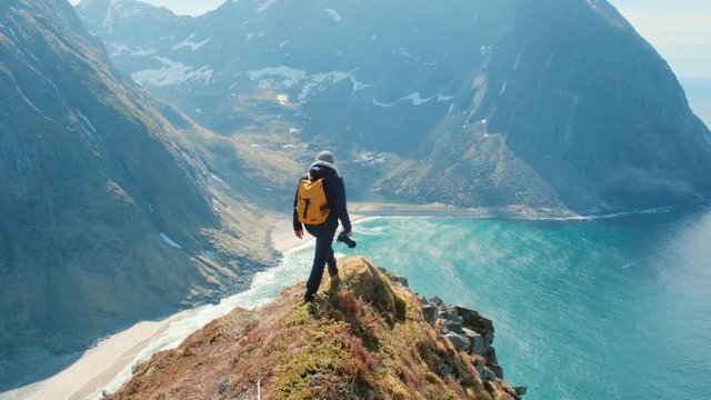Hiker man with a standing on the edge of the mountain in Norway in with strong wind