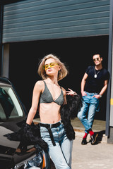 Fototapeta na wymiar stylish man and beautiful girl posing near car and garage