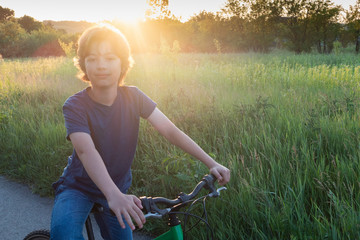 Obraz premium teenager riding a bicycle on the road summer sunlit