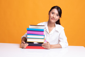 Happy young Asian woman read a book with books on table.