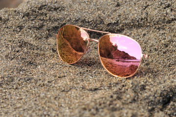 Sunglasses at the beach with sea reflection. Holidays, travel, vacation and happiness concept.