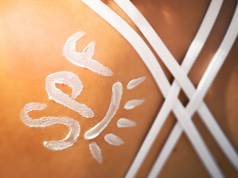 SPF shaped cream on the shoulder of young girl like a sign of protect from the sun. The reminder of the importance of using creams with SPF protection. Summer Travel Vacation Concept