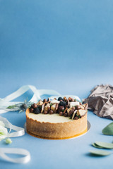 Sweet cake with berries and flowers, on a blue background with ribbons and draperies