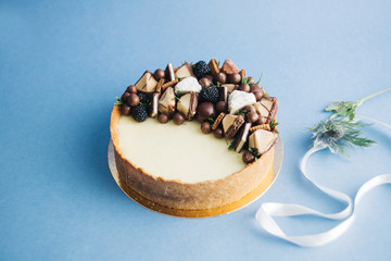 Sweet cake with berries and flowers, on a blue background with ribbons and draperies